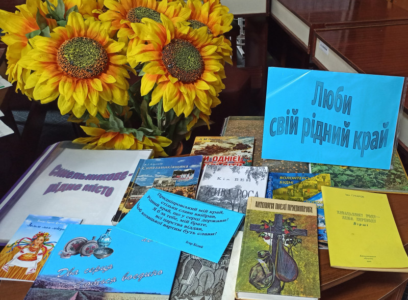 На столі  - підбірка видань про місто на тему: "Люби свій край", букет із соняхів.