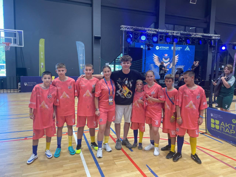 Дівчата та хлопці з нашої команди стоять півколом в однаковій спортивній формі рожевого кольору. З ними - інший хлопець.