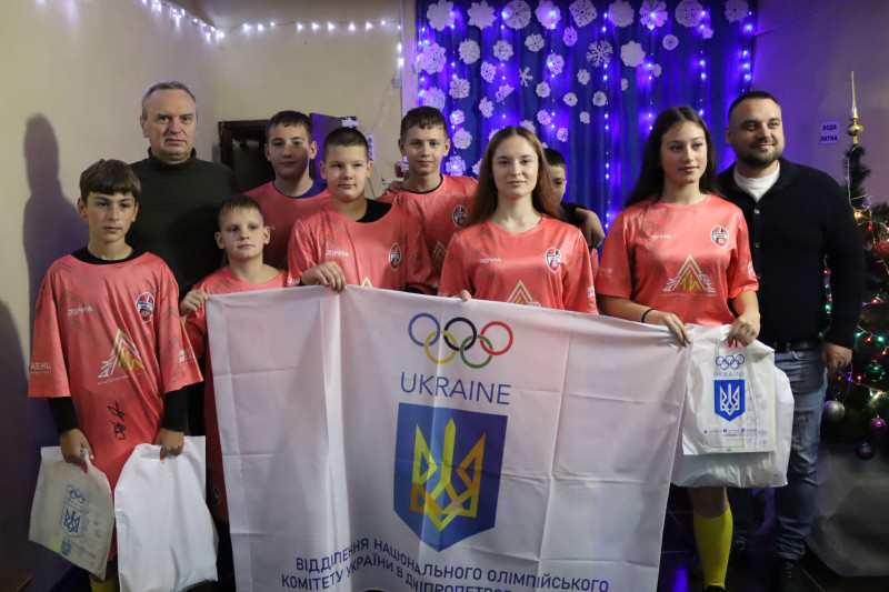 Спільне фото учасників команди «Запальні серця» з міським головою Дмитром Зражевським, представником НОК. У руках дітей  -  прапор відділення Національного олімпійського комітету України у Дніпропетровській області.