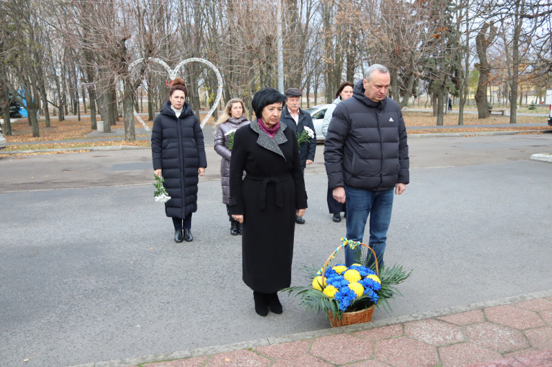 представники міської і районної влади стоять із квітами, кошиком із квітів  