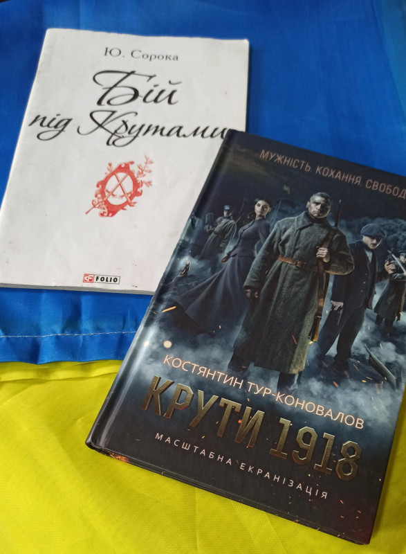 на синьо-жовтому  полотні лежать дві книги: Ю.Сороки "Бій під Крутами",  К.Тур-Коновалова "Крути 1918"