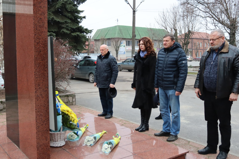 представники міської і районної влади стоять у підніжжя пам'ятного знаку, схиливши голови у хвилині мовчання    