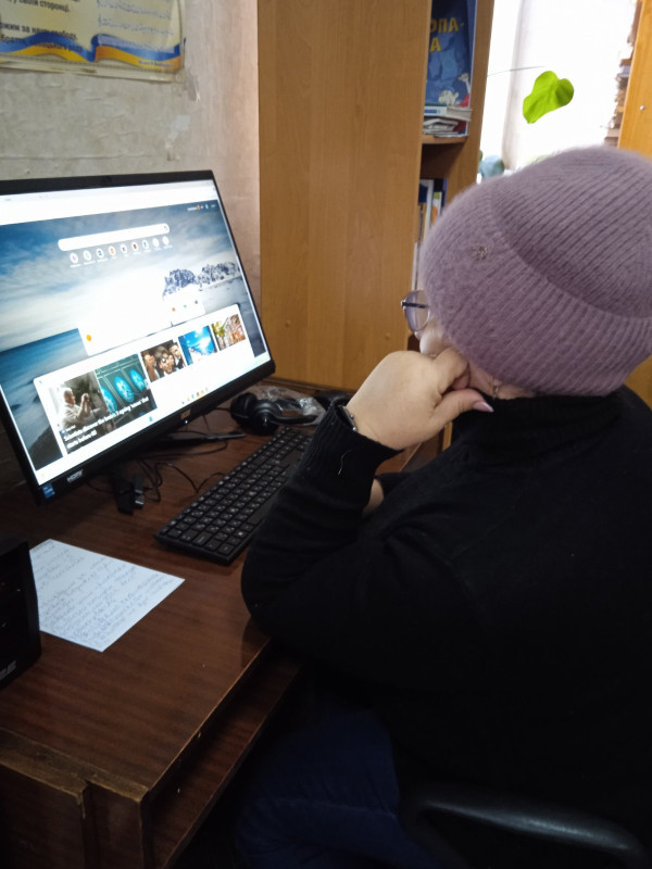 Жінка, відвідувачка бібліотеки, сидить перед комп'ютером, на якому встановлена спеціальна програма. На столі лежить клавіатура, навушники.