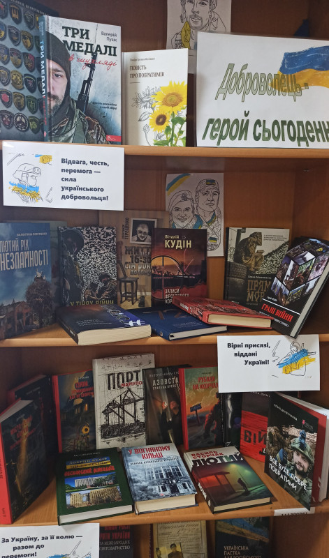 Виставка літератури у міській дитячій  бібліотеці до Дня українського добровольця. Шафа, на полицях якої книги відповідної тематики. 