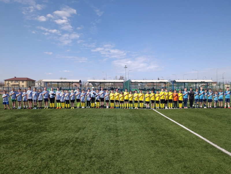 Юні футболісти вишикувалися на полі в одну лінію, приклавши праву руку до серця.