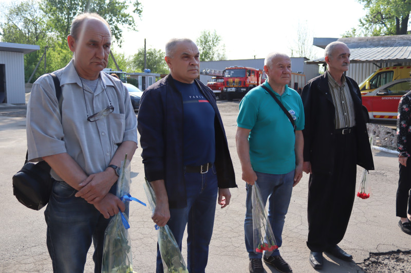 Ліквідатори аварії - чоловіки стоять у хвилині мовчання з квітами.