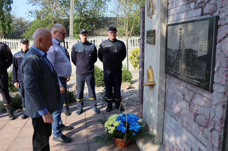 У хвилині мовчання стоять предаствники міської та районної влади, поставивши кошик із квітами до підніжжя пам'ятного знаку на честь ліквідаторів аварії на ЧАЕС. 