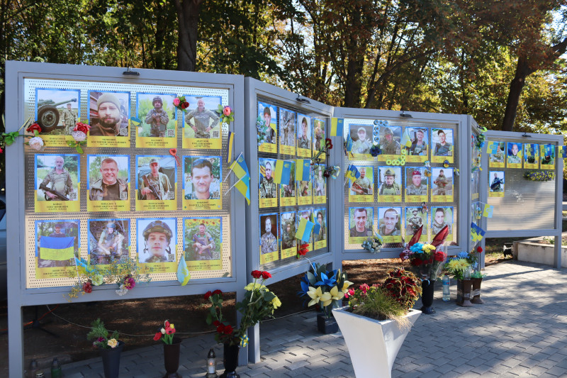 Пам'ятна дошка з фотографіями полеглих земляків, прикрашена квітами, прапорцями.