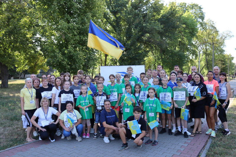 Спільне фото учасників заходу на фоні Державного Прапору України, дерев