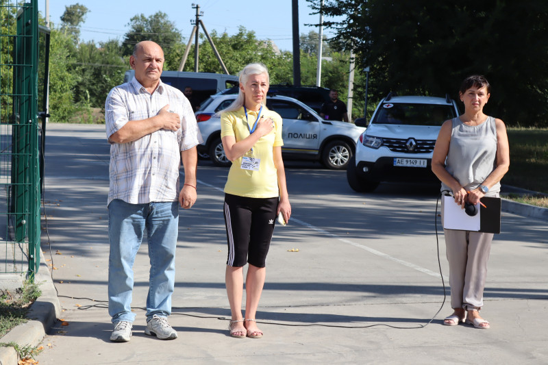 секретар Синельниківської міської ради Олена Заіка та керівник апарату Синельниківської районної військової адміністрації Валерій Воробйов стоять, поклавши праву руку на серце. Поряд - ведуча заходу.,