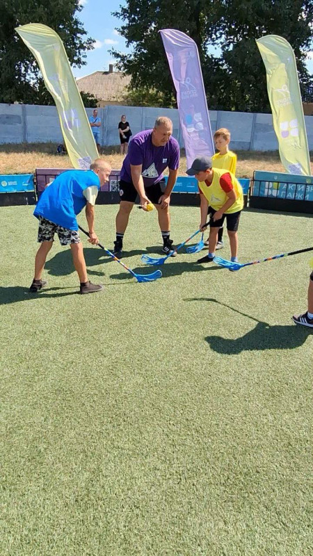 Діти на полі разом із тренером. У дітей в руках  ключки.