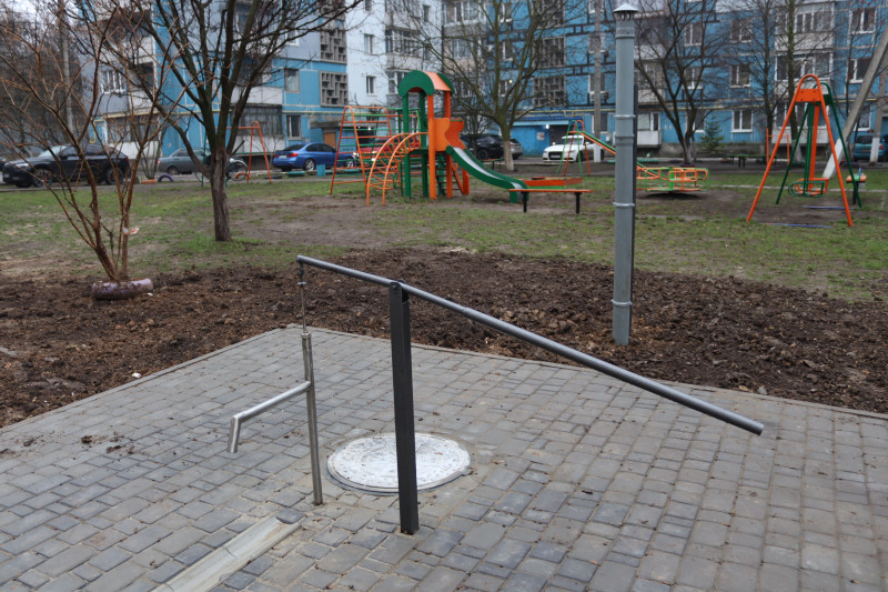 Криниця у дворі багатоповерхівки. Територія навколо викладена тротуарною плиткою.