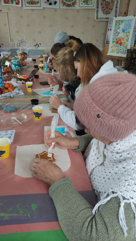 Учасниці заходу за роботою: сидять за столом, розмальовують пряники. 