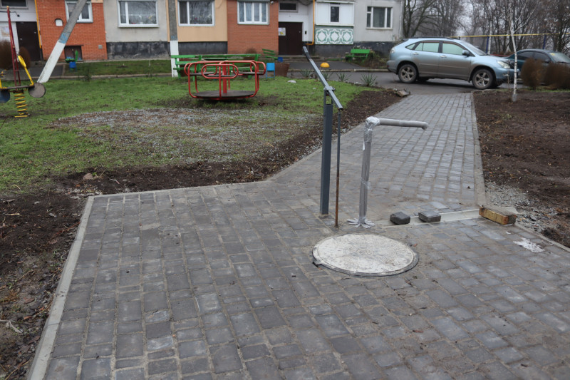 Нова криниця біля багатоповерхівки. Територія навколо викладена тротуарною плиткою.
