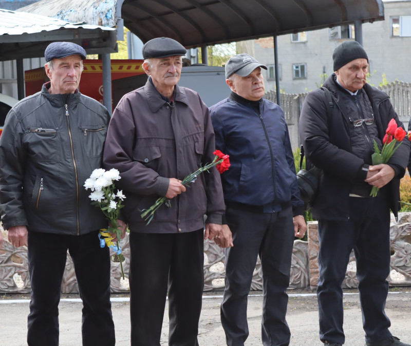 Чотири чоловіки - ліквідатори аварії стоять з квітами.