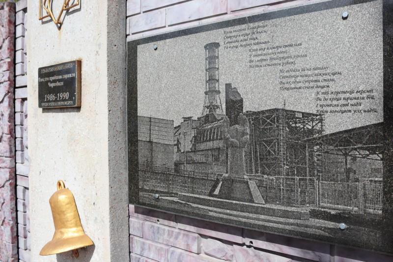 Фрагмент пам'ятного знака на честь ліквідаторів: фото енергоблока, символічний дзвін, дати.