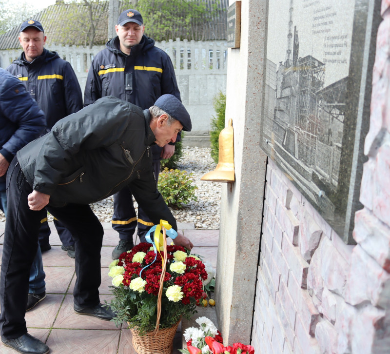 Чоловік - ліквідатор аварії  покладає квіти до пам'ятного знака.