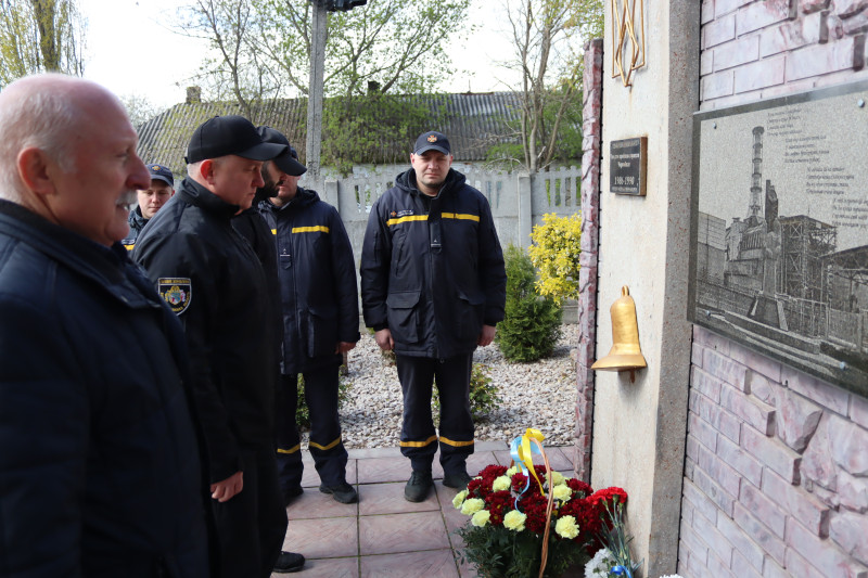 Учасники заходу - правоохоронці, представники влади стоять перед пам'ятним знаком. У підніжжя -  квіти.