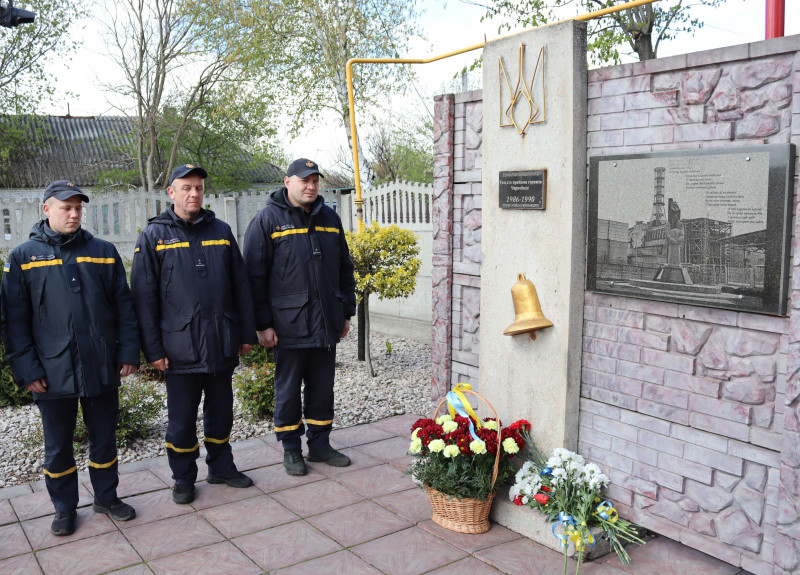 Наші сучасні герої - рятувальники поруч із пам'ятним знаком. У підніжжя - квіти.